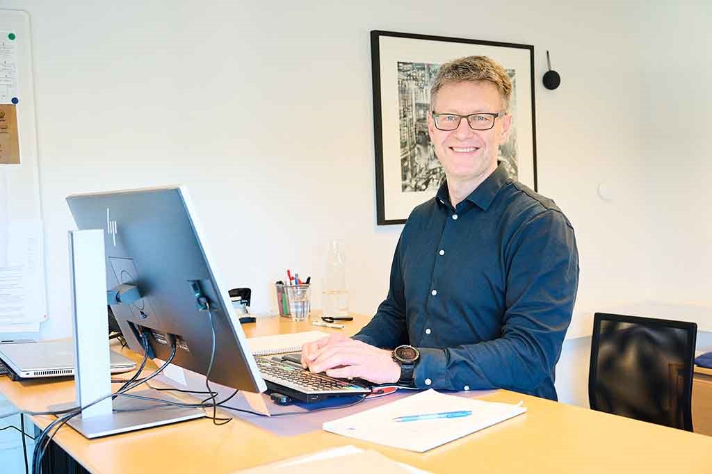 En smilende mand med computer - Drifts- og økonomichef hos PIT Hegn Ringe