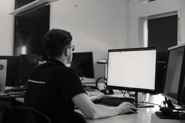 en programmør der sidder på sit kontor foran computerskærmen og koder.